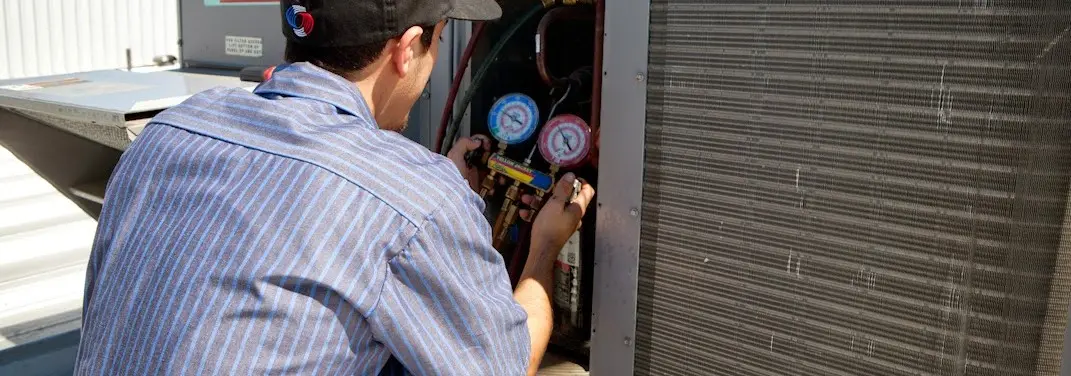 HVAC technician servicing a condenser unit in Robeson